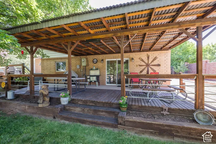 Expansive covered deck featuring a corrugated metal roof, exposed wood beams, wood decking, and direct access to the brick exterior