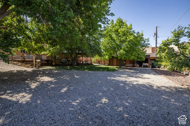 Gravel parking area featuring mature trees and a multi-level wood deck