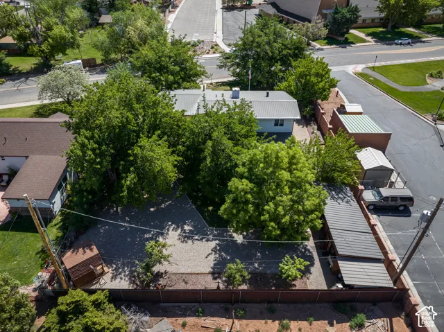 Property featuring a gravel lot, mature trees, a detached storage shed, a covered carport, and a brick privacy fence
