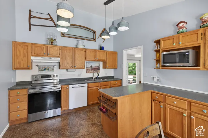 Kitchen featuring wood cabinetry, dark countertops, a stainless steel range, and a white dishwasher