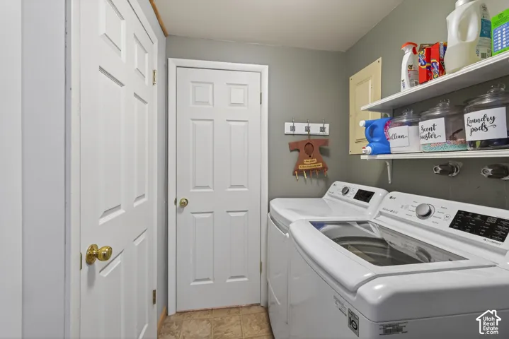 Dedicated laundry room featuring tile flooring, neutral wall color, and white shelving for storage
