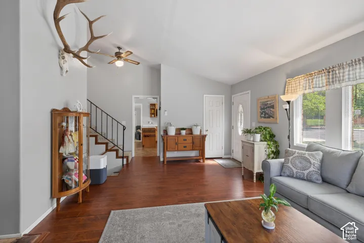 Living area featuring wood-finish flooring, vaulted ceilings, and a ceiling fan