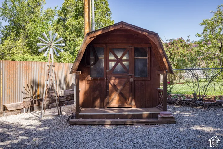 Barn-style shed featuring a wood door with X-detailing and a small front porch
