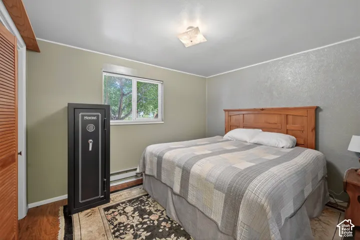 Bedroom featuring wood-finish flooring, a window with exterior tree views, and a ceiling-mounted light fixture