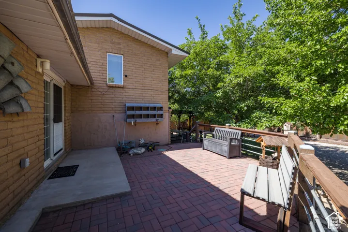 Brick exterior with a window and a white-framed sliding glass door opening onto a paver patio