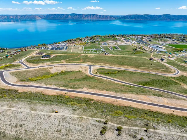 Expansive land parcels with paved road infrastructure, featuring a distant lake and mountain backdrop