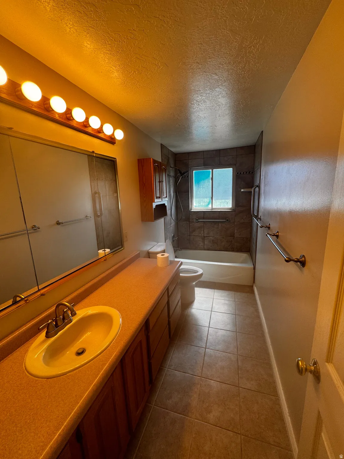Full bathroom featuring a single vanity with an integrated sink and brushed nickel faucet, a large mirrored medicine cabinet, and wood-finish cabinetry