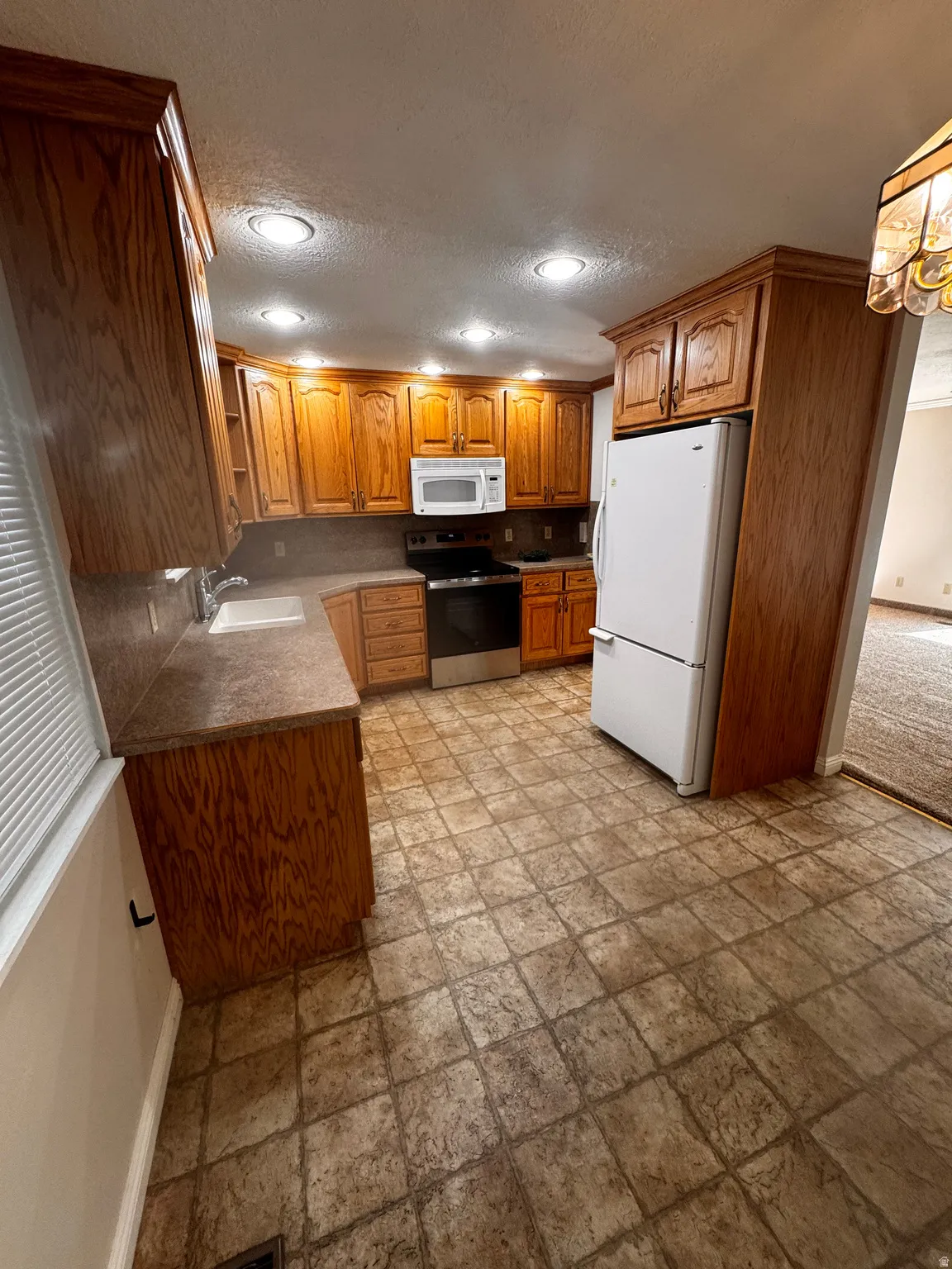 Kitchen featuring wood cabinetry, stone-look countertops, and recessed lighting