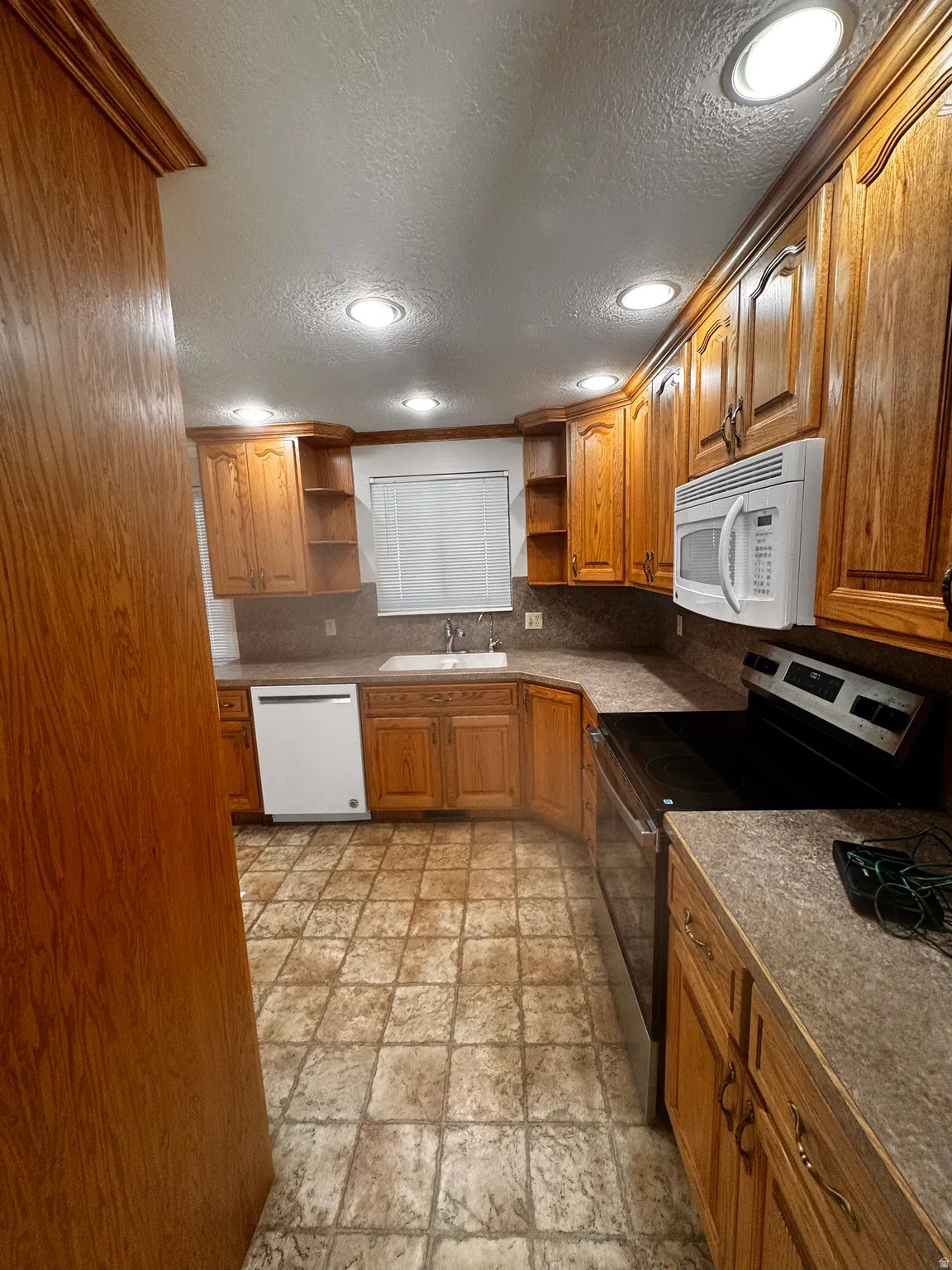 Well-appointed kitchen featuring wood-finish cabinetry, recessed lighting, and a white built-in microwave