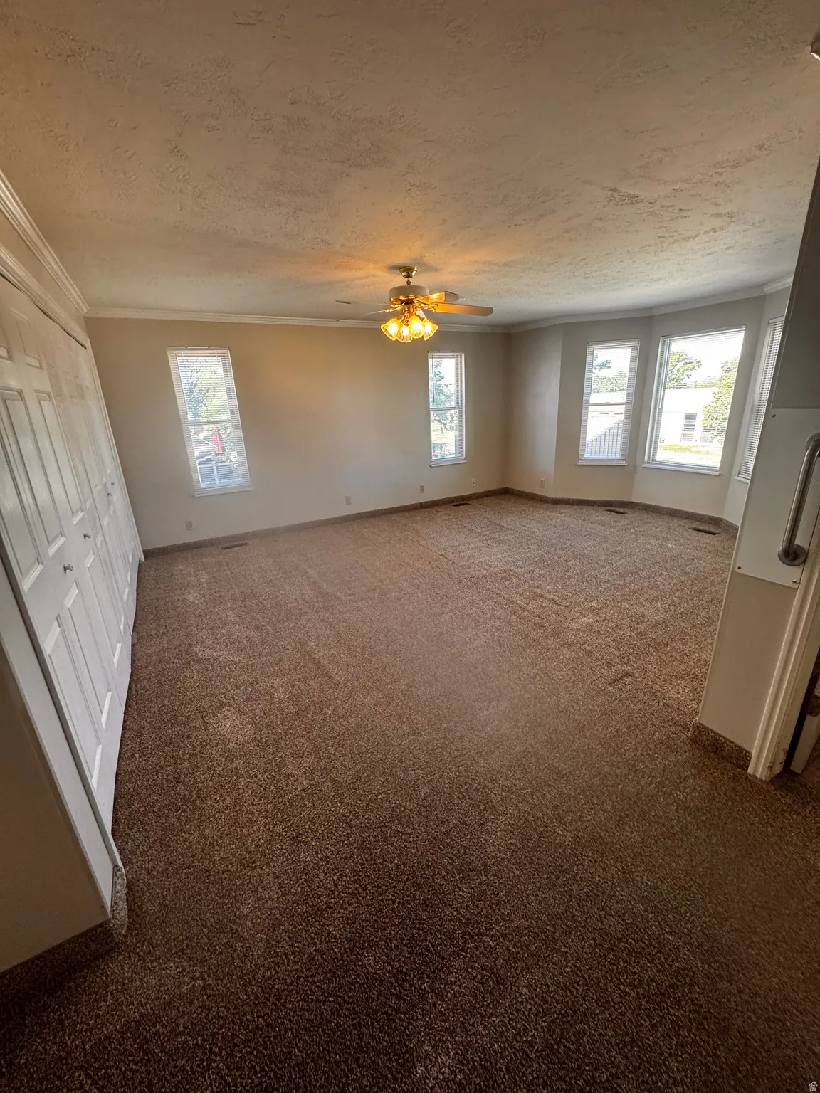Spacious room featuring broadloom carpeting and a ceiling fan with integrated lighting
