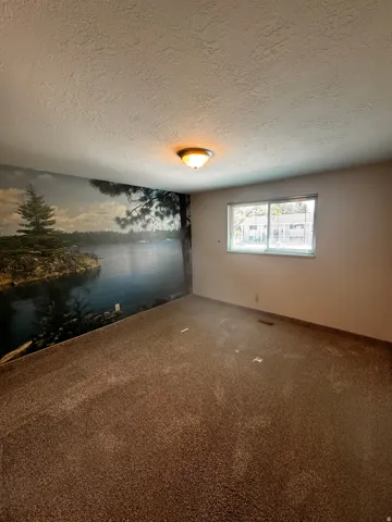 Room with a wall-mounted mural, recessed window, textured ceiling, and flush-mount ceiling light