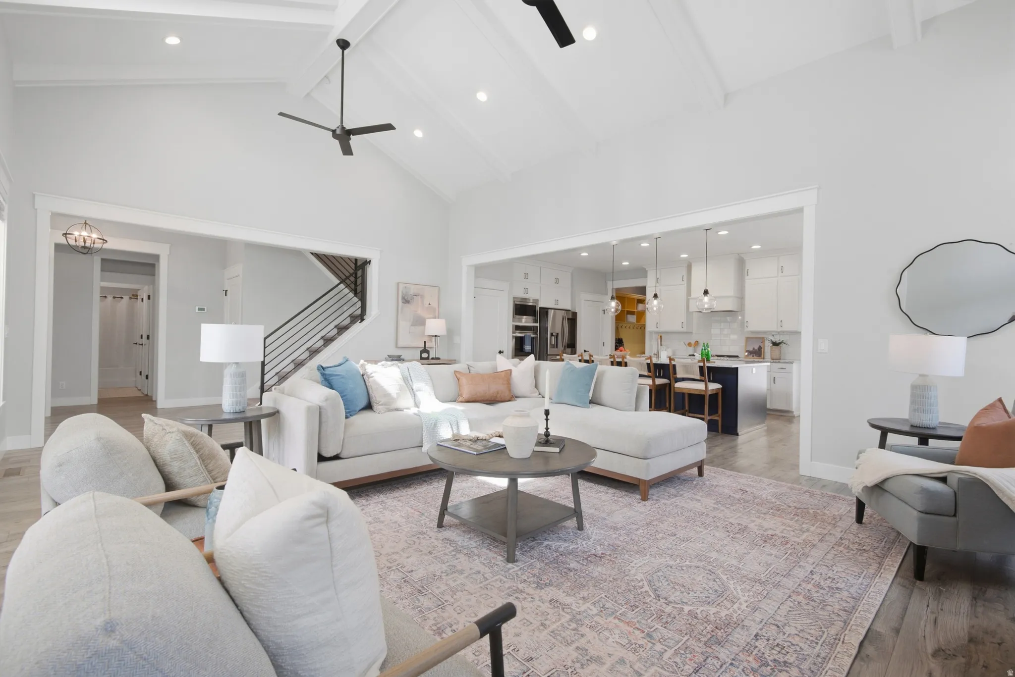 Vaulted ceiling with exposed beams, wood-finish flooring, recessed lighting, open concept layout, and a contemporary staircase with metal railings