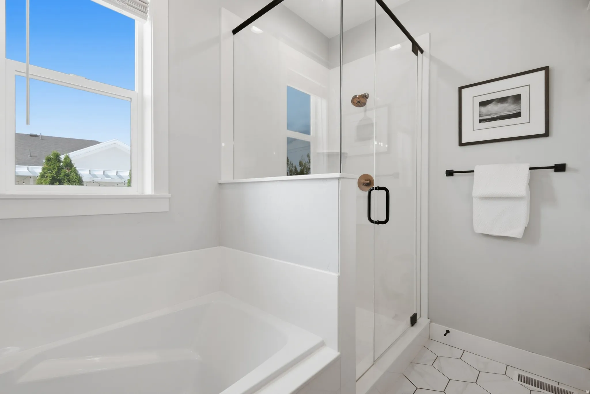 Primary Bathroom. Deep-soaking tub, walk-in shower with clear glass enclosure, matte black hardware, and hexagonal floor tiling