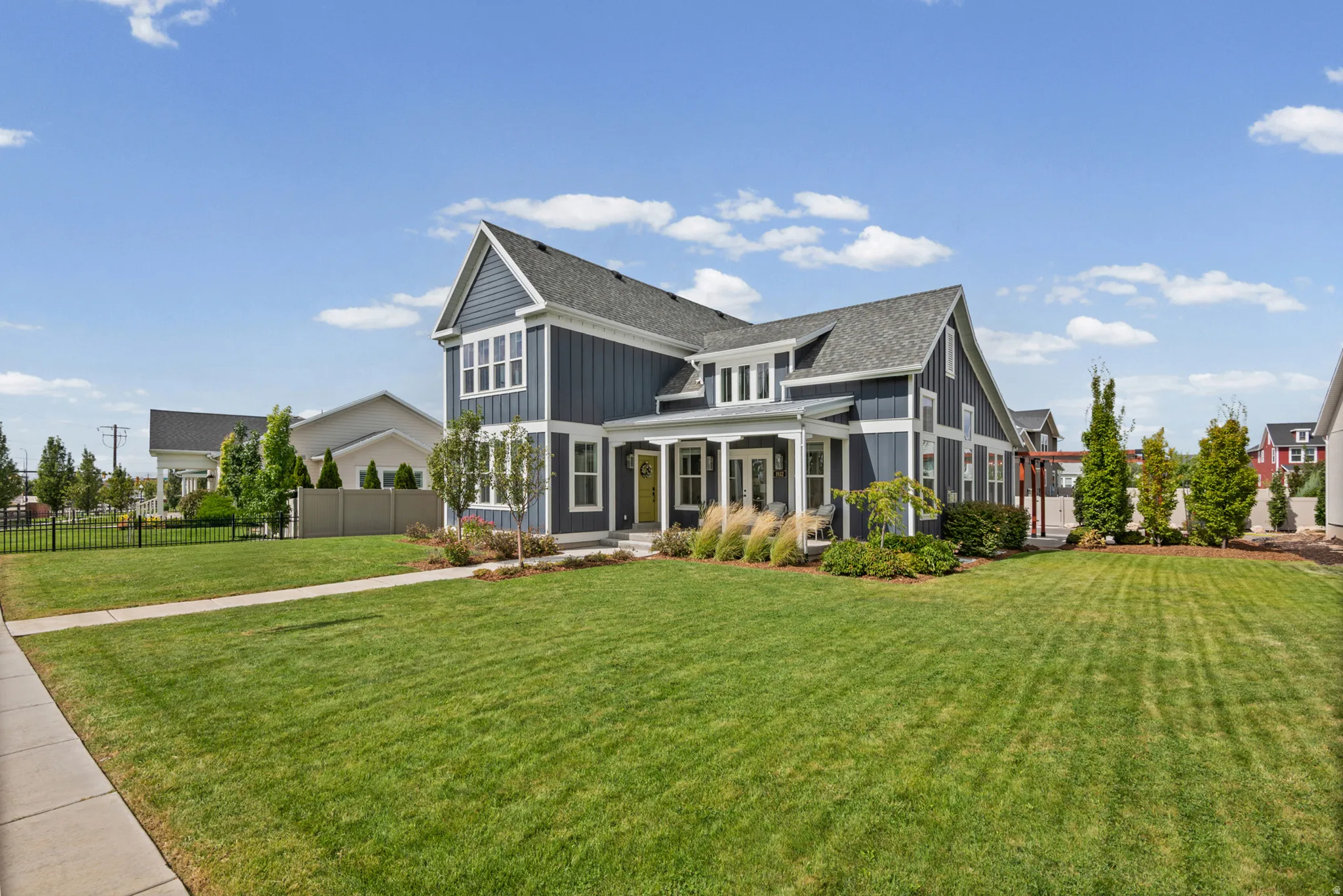 Two-story residence featuring a dark blue siding exterior, a prominent front gable, a covered porch with white columns, and a landscaped front yard with a paved walkway