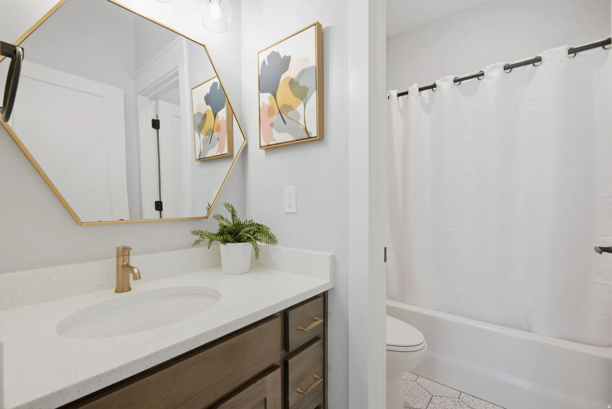 White solid surface countertop, gold-finish faucet, under-mount sink, dark wood-finish vanity, and white bathtub