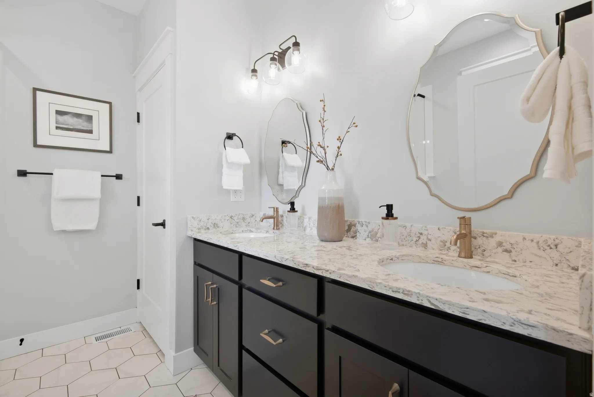 Primary bathroom. Double vanity with dark cabinetry, integrated sinks, and light-toned countertops