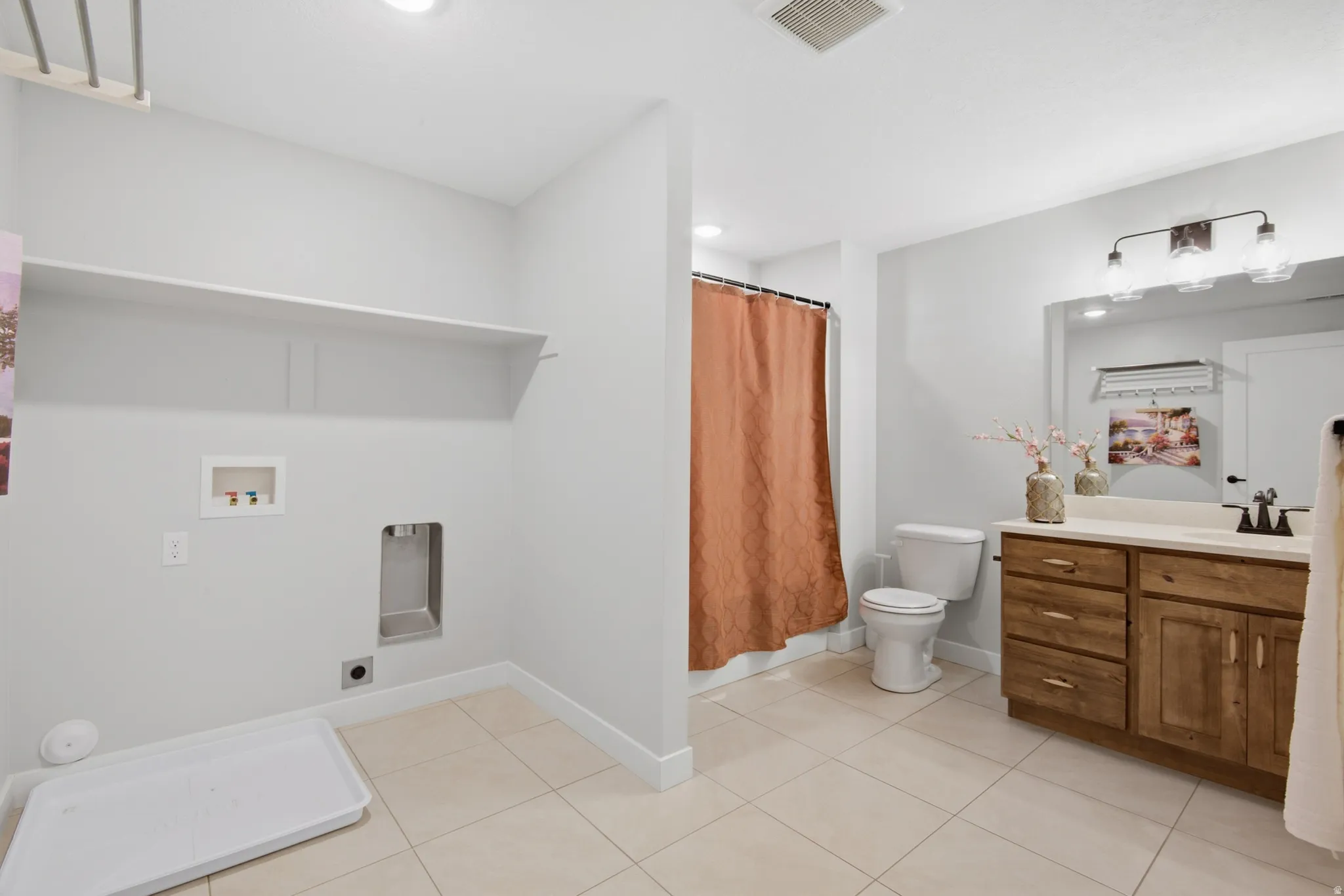 Basement ADU bathroom and laundry room. Built-in shelving, tile flooring, wood-finish vanity with countertop, and recessed lighting