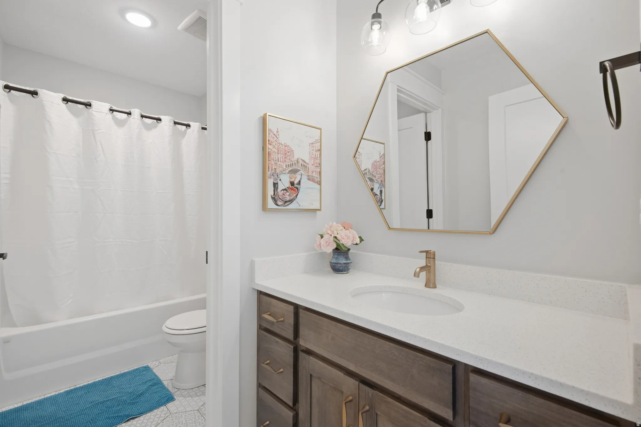 Bathroom featuring a white bathtub, toilet, and a vanity with a white countertop and wood-finish cabinetry