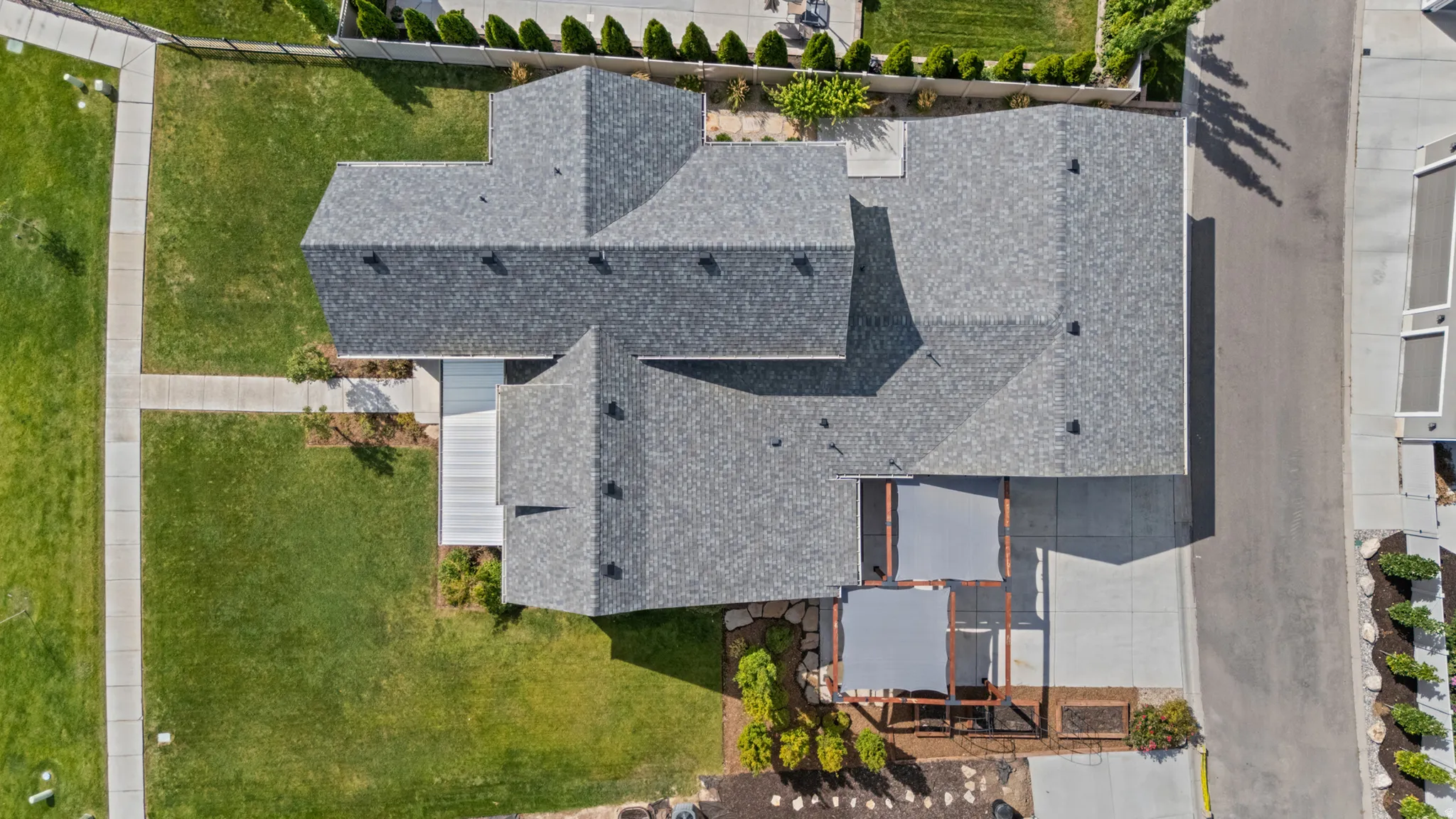 Expansive gabled roofline, concrete driveway, front walkway, and covered patio with retractable shade canopies
