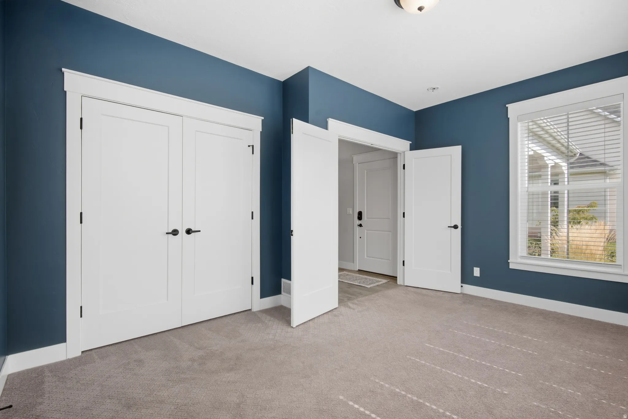 Bedroom 2 with Carpeted flooring, white trim, white doors, and a window with blinds