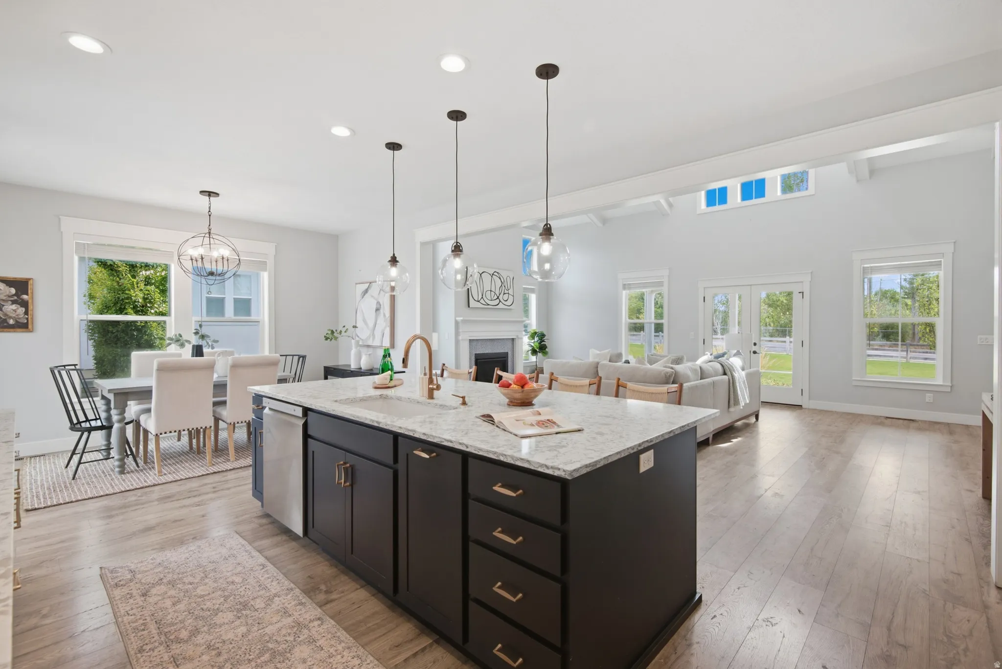 Kitchen island with granite-finish countertop, wood-finish flooring, recessed lighting, high vaulted ceilings, and French doors