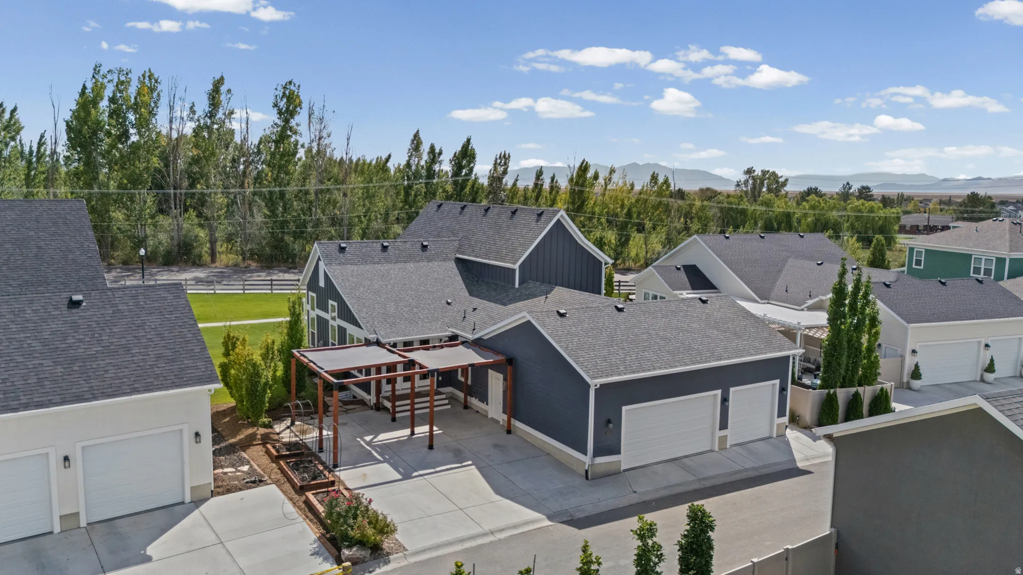 Contemporary siding with pitched rooflines, attached two-car garage, and a covered pergola