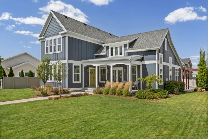 Two-story exterior with board and batten siding, covered front porch, and a lush lawn