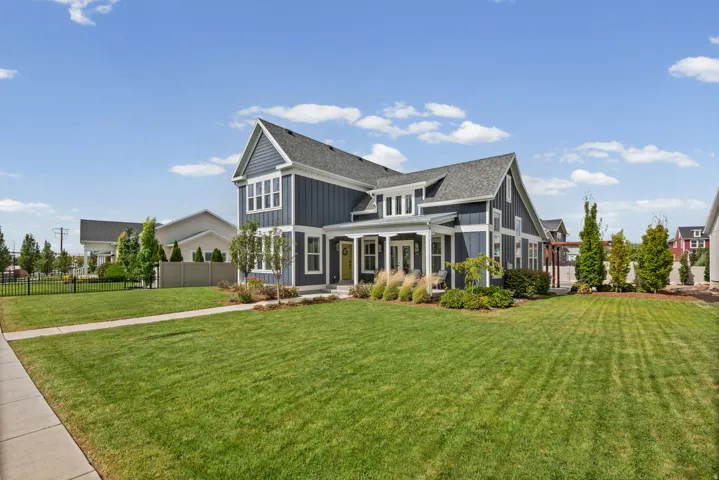 Two-story residence featuring a dark blue siding exterior, a prominent front gable, a covered porch with white columns, and a landscaped front yard with a paved walkway