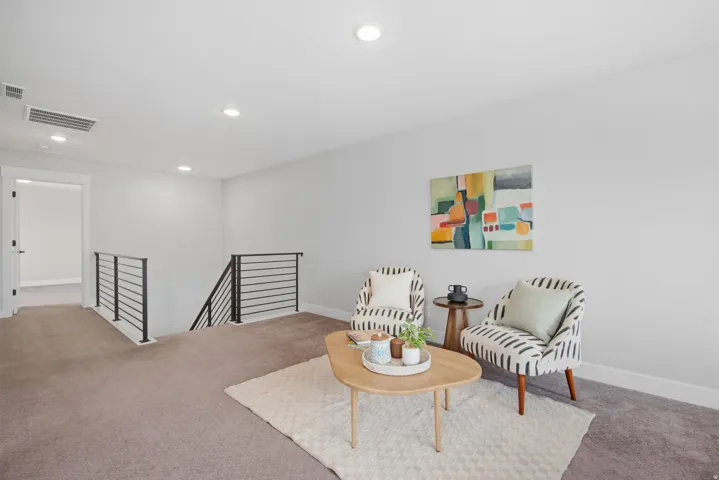 Open loft space with recessed lighting, carpet flooring, and contemporary horizontal metal railings