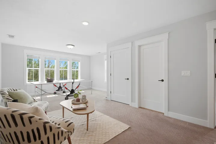 Recessed lighting, large windows, light gray wall paint, white trim, and light brown carpeting