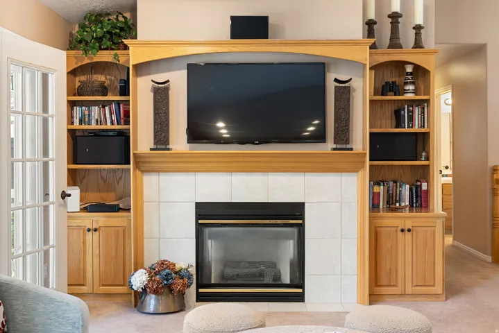 Custom built-in entertainment center featuring a wood mantel, tile fireplace surround, and integrated shelving
