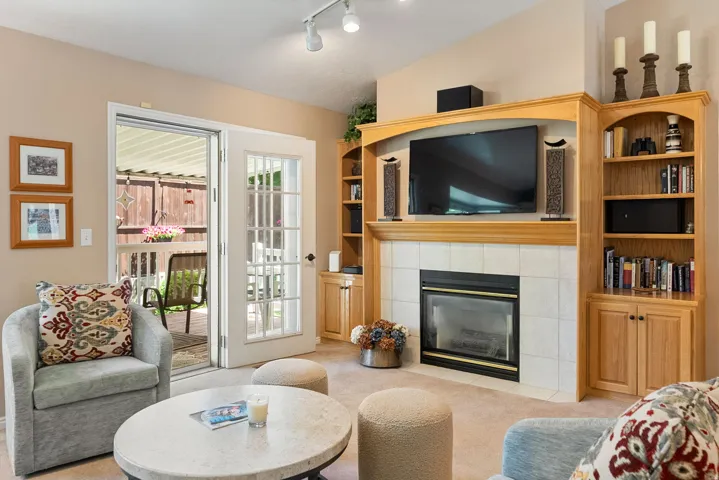 Living area featuring a natural wood built-in media center with integrated shelving and cabinetry, a fireplace with a light-tiled surround, and recessed lighting