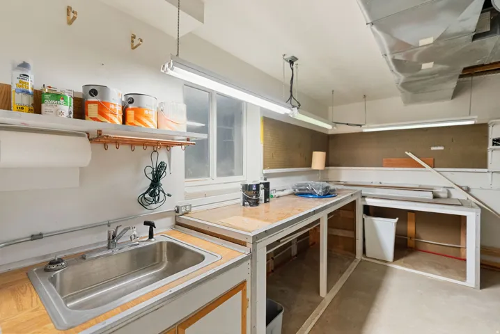 Dedicated workspace featuring a stainless steel utility sink, wood-finish countertops, built-in shelving, and practical pegboard storage