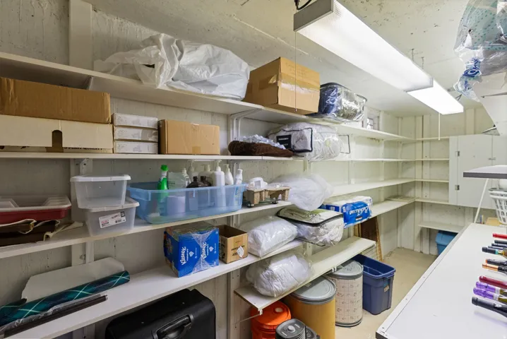 Spacious utility room featuring extensive built-in shelving, durable concrete block walls, and overhead fluorescent lighting