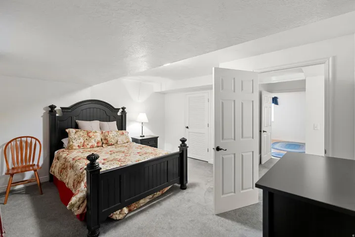 Carpeted bedroom featuring white walls and a six-panel interior door with black hardware
