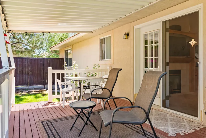 Covered outdoor patio featuring wood-finish flooring, a white railing, and a light-colored stucco exterior