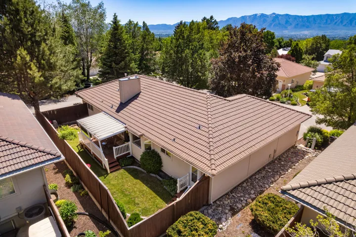 Aerial perspective showcasing a property with a tile roof, a covered deck, and a fenced backyard