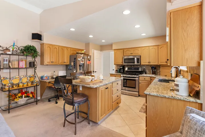 Spacious kitchen featuring an island, light wood cabinetry, stainless steel appliances, granite countertops, and recessed lighting