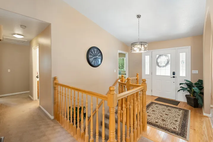 Entryway featuring wood-finish flooring, a white paneled front door with decorative glass inserts, and a contemporary pendant light fixture