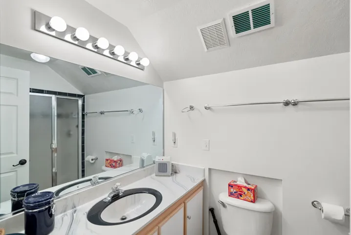 Bathroom featuring a white vanity with an undermount sink, a marble-patterned countertop, and a large mirror