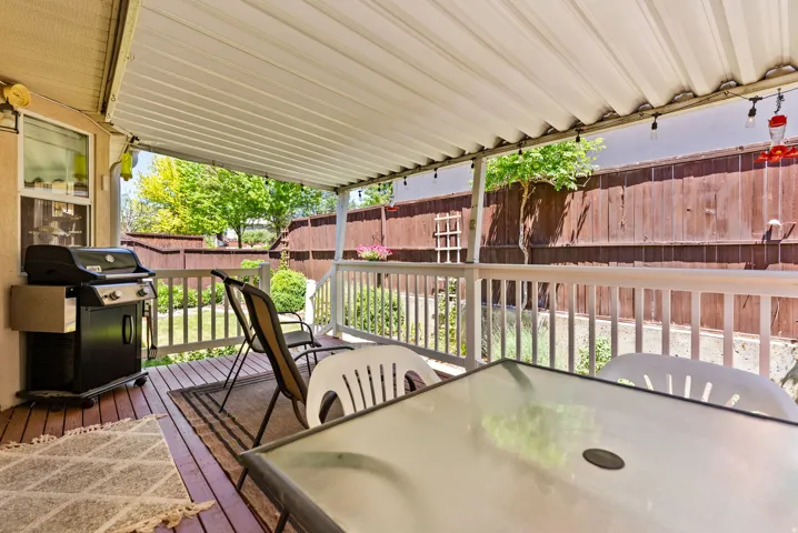 Covered outdoor deck featuring wood-finish flooring and white railings