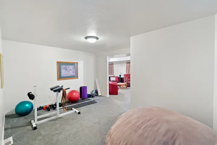Carpeted room with white walls, recessed ceiling light, and a partial wall separating spaces