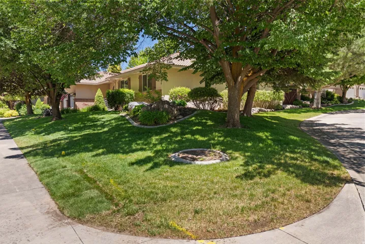 Expansive corner lot featuring mature shade trees, established landscaping, and a curved sidewalk
