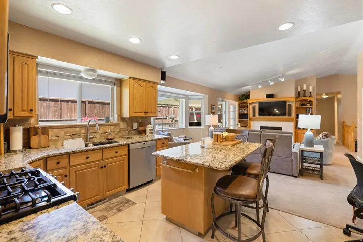 Open-concept kitchen featuring light wood cabinetry and granite countertops