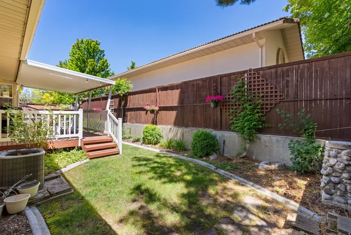 Covered wood deck with white railings and stained steps leading to a grass lawn