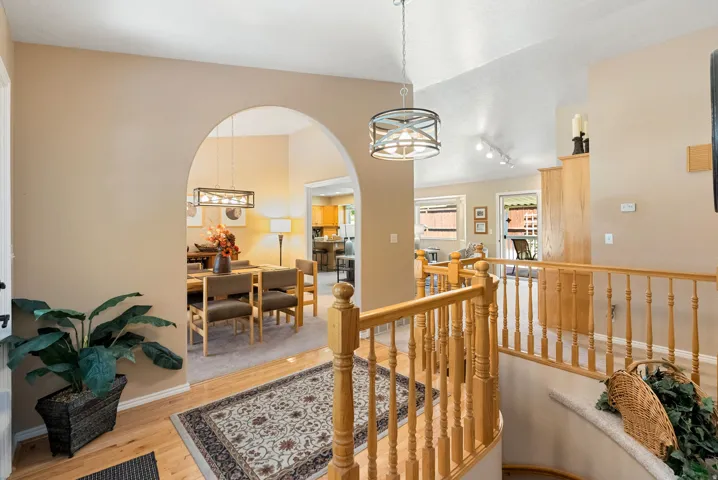 Entryway featuring light wood-finish flooring, an arched doorway, and a wooden staircase with balusters