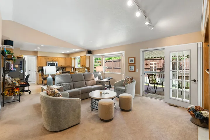 Open-concept living space featuring carpet flooring, track lighting, and a vaulted ceiling
