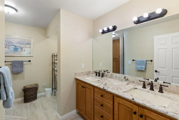 Primary bathroom with dual vanity with undermount sinks, stone countertops, and bronze-finish faucets