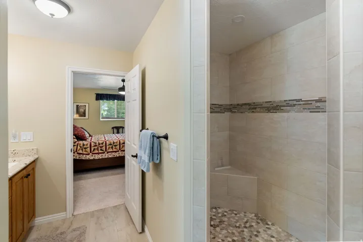 Primary bathroom with walk-in shower featuring natural stone pebble flooring, a tiled bench, and a decorative mosaic tile band