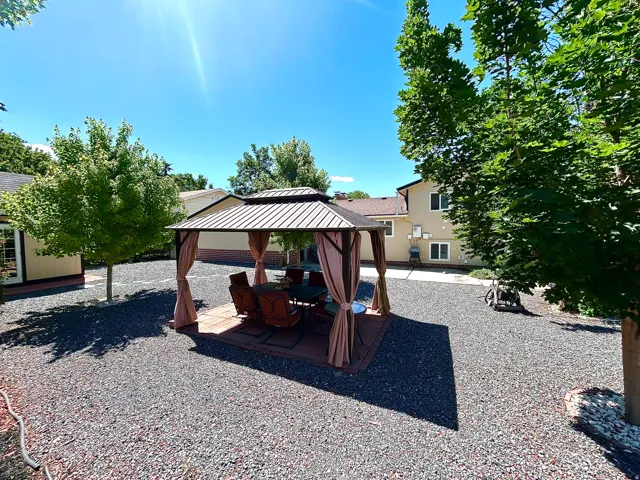 Spacious outdoor area featuring a central gazebo with a metal roof, a paver stone patio base, and surrounding gravel landscaping